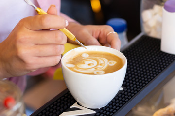 Barista girl makes latte art in a coffee shop, a woman draws a beautiful bear on coffee foam. Close-up