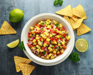 Bowl of fresh Mango Salsa with nachos chips and herbs. Healthy Vegan, Vegetables food.