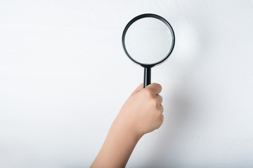 Magnifier in a children's hand on a white background. Close-up
