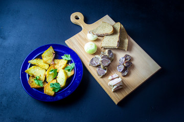 sprinkled boiled potatoes on a blue plate sprinkle with herbs, next to a board with bacon and onions