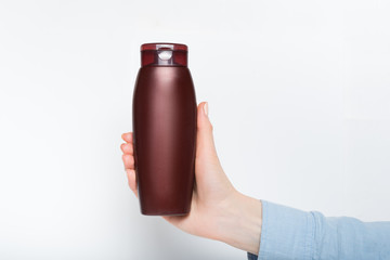 Brown bottle for cosmetic in a female hand. Mockup. White background