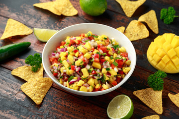 Bowl of fresh Mango Salsa with nachos chips and herbs. Healthy Vegan, Vegetables food.