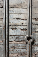 Closeup view of old weathered rusty wooden door, with cracked painted horizontal planks and decorative elements