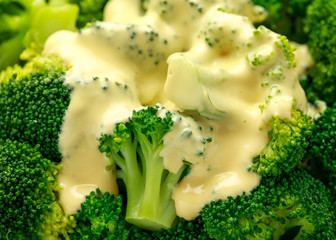 Broccoli with cheese sauce in white bowl on wooden table