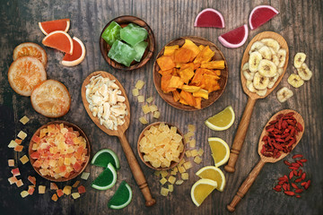 Dried fruit selection in wooden spoons & bowls on rustic wood background. Health food high in antioxidants, minerals, vitamins and anthocyanins. Flat lay., top view.