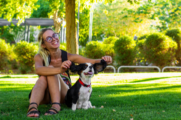 Obraz premium human and animal portrait photography of smiling girl without make up and sunny King Charles Cavalier in green grass meadow of sunny park outdoor city square space for walking with pets, copy space