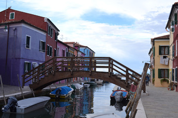 Fototapeta na wymiar Wooden bridge over the canal on the island of Burano. Traditional street with colorful houses.
