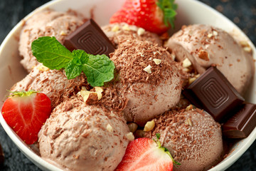 Chocolate Ice Cream with dark chocolate bars, strawberry and hazelnuts in a white bowl