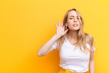 young pretty blonde woman looking serious and curious, listening, trying to hear a secret...