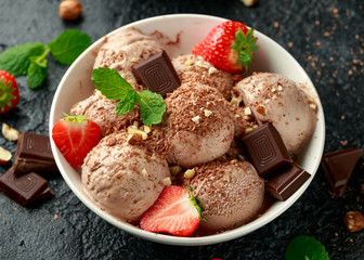 Chocolate Ice Cream with dark chocolate bars, strawberry and hazelnuts in a white bowl