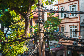 Messy tangled wires around a power pole in Hanoi, Vietnam. Close up shot showing the mess and disorder that the wires pose