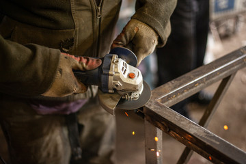 A man processes metal with a grinder.