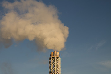 Pipe heating system with white steam against the blue sky