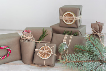 Pile of presents and gifts wrapped in craft paper with decoration on white wooden background. Holiday zero waste concept.