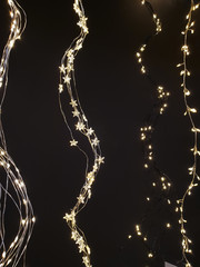 Star and sleeve Christmas lights, fairy lights hanging in a wave form next to each other on dark background.