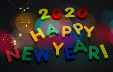 Happy New Year 2020! Colored text made up of a children’s alphabet, illuminated by a garland and lens leaks