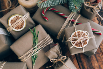 Presents and gifts wrapped in craft paper with decoration on brown wooden background. Holiday zero...
