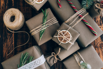Presents and gifts wrapped in craft paper with decoration on brown wooden background. Holiday zero...