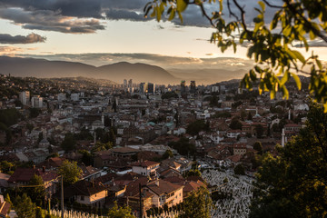 Fototapeta na wymiar Arial view of a city from a hill during sunset, Sarajevo Bosnia and Herzegovina. The whole city with mountains layers in the background.