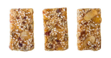 Three sweet shortcrust biscuits glazed by honey coating isolated on white background. Set of yummy rectangular Xmas cookies full of sliced almonds, dried fruits, sesame and sunflower seeds or raisins.