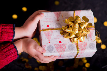 Little child gives a gift with a big golden bow for the New Year.