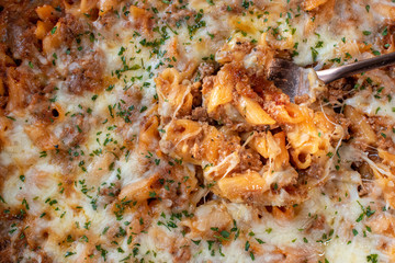 spoonful of baked macaroni pasta with tomato sauce and cheese