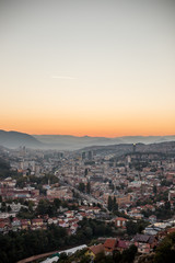 Fototapeta na wymiar Arial view of a city from a hill during sunset, Sarajevo Bosnia and Herzegovina. The whole city with mountains layers in the background.