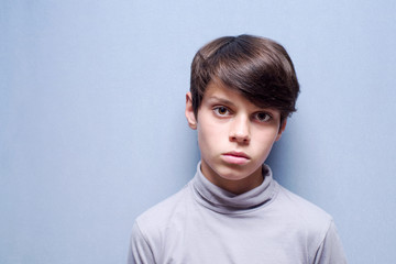 Portrait of a sad boy with a blue background