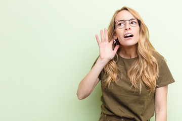 young pretty blonde woman looking serious and curious, listening, trying to hear a secret...
