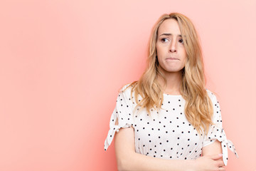 young pretty blonde woman doubting or thinking, biting lip and feeling insecure and nervous,...