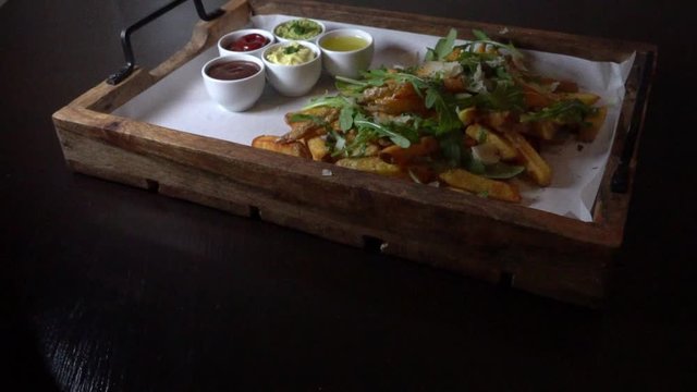 French fries made of fresh tomatoes with different sauces, rocket salad and parmesan cheese on a wooden tray