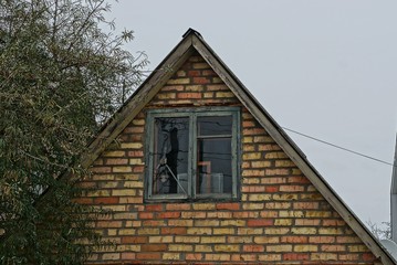 facade of a brown brick house with an attic and one window 