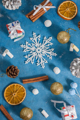 Christmas and New Year pattern made of snowflakes,cookies, cinnamon, orange, cones and marshmallows on a blue background with stars. Christmas, winter, new year concept. Flat lay, top view, copy space