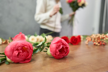 European floral shop concept. Florist woman creates red beautiful bouquet of mixed flowers. Handsome fresh bunch. Education, master class and floristry courses. Flowers delivery.