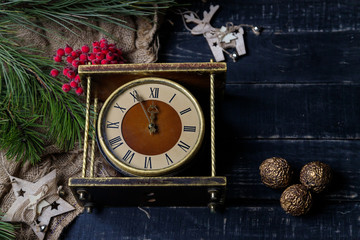 Brown vintage clock, pine branches and wooden reindeer toy on black background. Merry Christmas,...