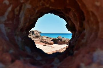 View through a hole in the Rock at a Tropical Beach, Broome, Western Australia, Australia
