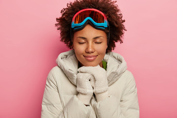 Woman skier enjoys nice snowboarding time, dressed in white down padded coat, white soft gloves,...