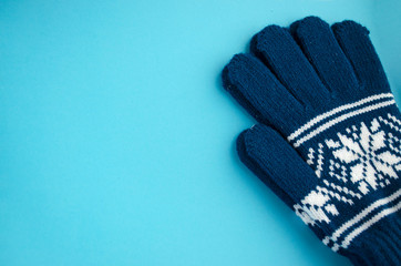 Pair of gloves isolated on the blue background. Blue mittens close-up with copy space.