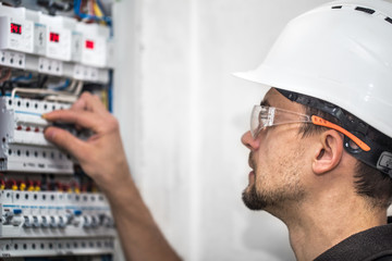 Man, an electrical technician working in a switchboard with fuses. Installation and connection of electrical equipment. Close up.