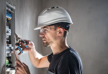 Man, an electrical technician working in a switchboard with fuses. Installation and connection of...