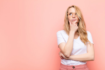 young pretty blonde woman thinking, feeling doubtful and confused, with different options,...