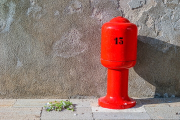 Number 13 on a bright red pillar in front of a beige wall