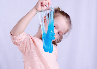 Adorable little girl holding slime toy, worldwide popular self made toy. Kid playing with slime...
