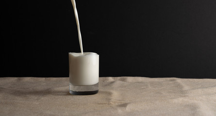 Pouring milk into invisible glass, abstract creative idea. Copy space, black background.