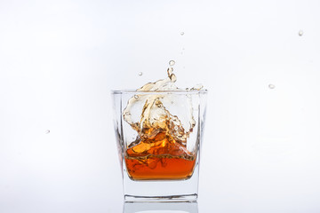 Alcohol in the glass. Whiskey and ice. Rum with ice. Brown brandy with splashes. Ice cube falls...