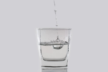 Water or alcohol drops falls in a glass on a white background. Close-up photo