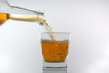 Double whiskey being poured into a glass against white background