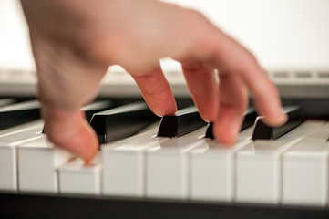 Fototapeta premium Male hand plays the piano keyboard isolated on white background. Close-up shallow depth of focus of the part. Rear view from below. Mechanics of the movement of keys are clearly visible.