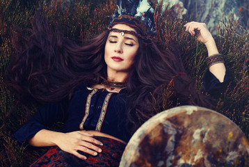 beautiful shamanic girl with shaman frame drum in the nature.