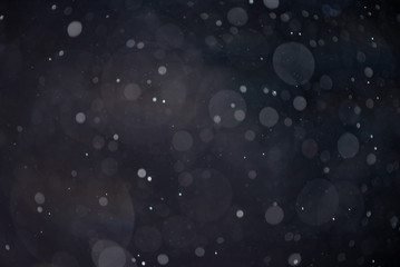 Abstract falling snow or rain bokeh texture overlay on blue background.